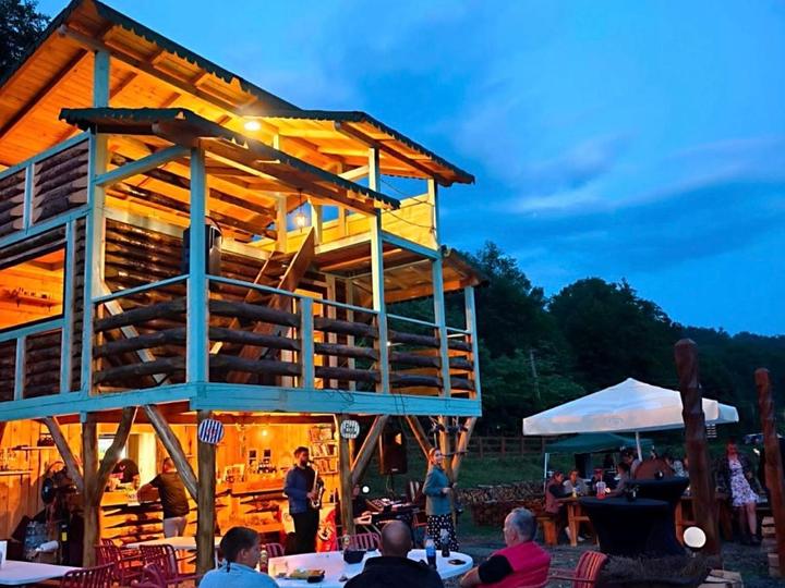 The wooden cabin at blue hour, with people at the tables below